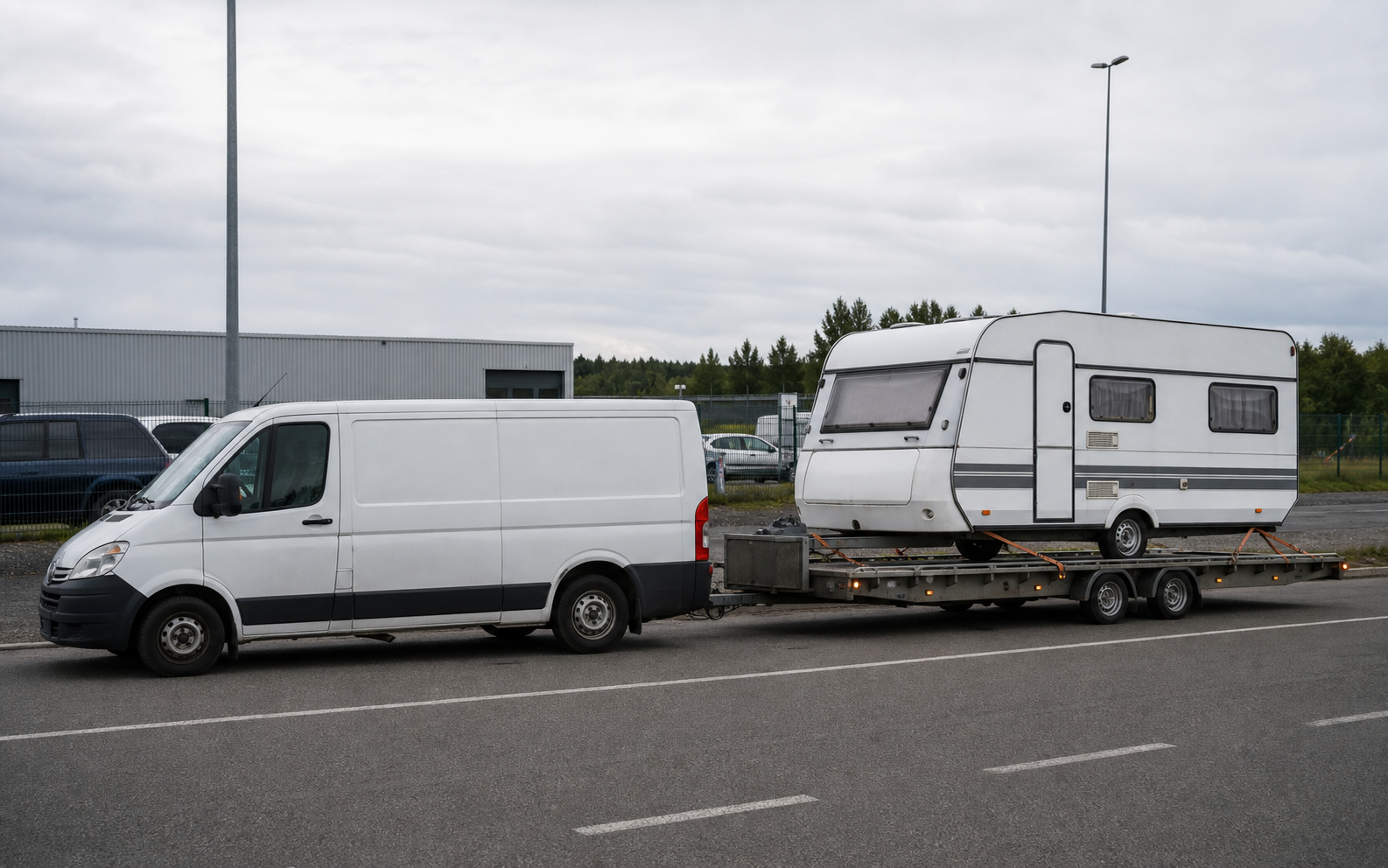 Bestelbus die een caravan op transporttrailer voortsleept